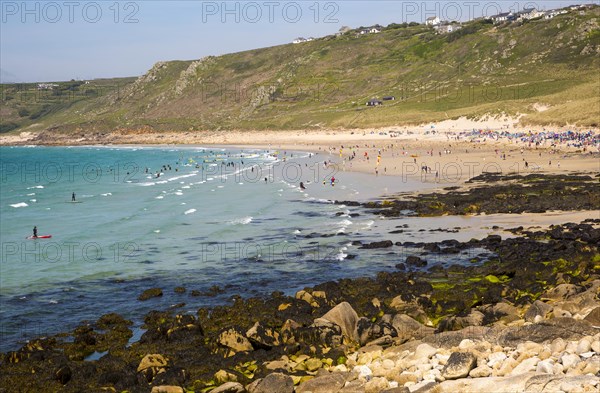 Coastal scenery with busy crowded sandy beach, Sennan Cove, Land's End, Cornwall, England, UK