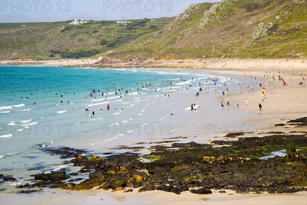 Coastal scenery with busy crowded sandy beach, Sennan Cove, Land's End, Cornwall, England, UK