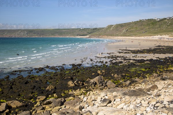 Coastal scenery with busy crowded sandy beach, Sennan Cove, Land's End, Cornwall, England, UK