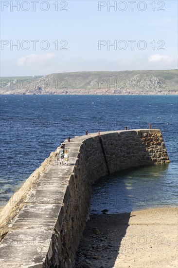 Woman and girl walking on breakwater quay, Sennen Cove, Land's End, Cornwall, England, UK