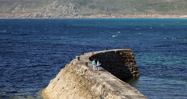 Woman and girl walking on breakwater quay, Sennen Cove, Land's End, Cornwall, England, UK