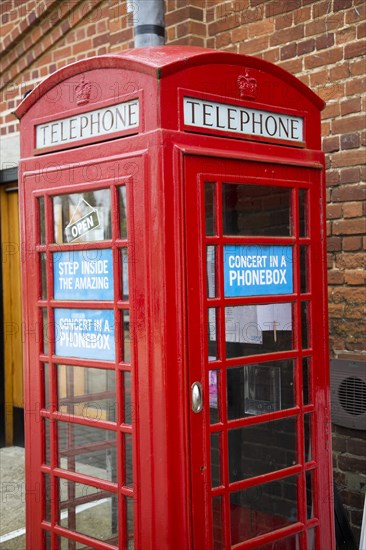 Concert in a Phonebox in old red traditional phone box booth, Snape Maltings, Suffolk, England, UK