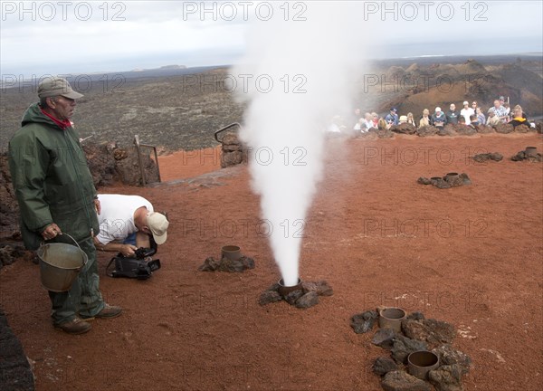 Tourists watch steam rise from geyser spout, Parque Nacional de Timanfaya, national park,