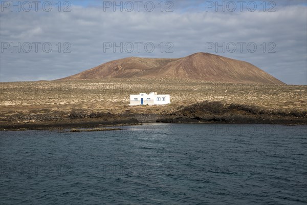 Isolated whitewashed house and Agujas Grandes volcano, La Isla Graciosa, Lanzarote, Canary Islands,