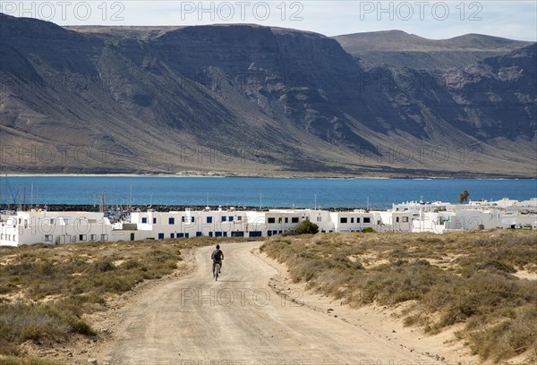 Cyclist dirt track leading to Caleta de Sebo village on Graciosa island, Lanzarote, Canary Islands,