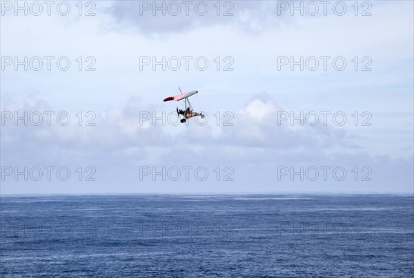 Person flying microlight plane over the ocean, Caleta de Caballo, Lanzarote, Canary islands, Spain,