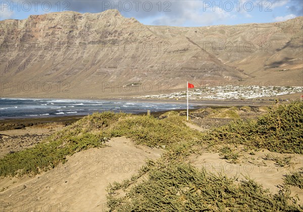 Red flag flying warning of bathing danger, La Caleta de Famara, Lanzarote, Canary islands, Spain,