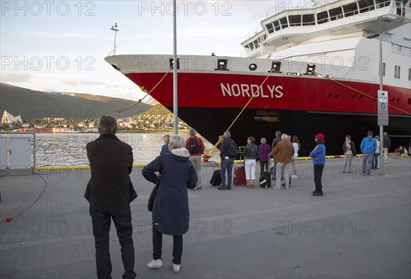 Hurtigruten ferry ship Nordlys with waiting passengers moored at Tromso, Norway, Europe