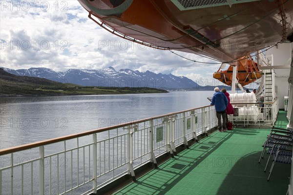 Two people on deck viewing scenery on Hurtigruten ferry ship, near the Arctic Circle crossing,