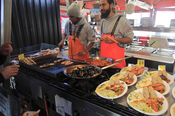 Street stall restaurant cooking fish meals in Torget market, Bergen, Norway, Europe