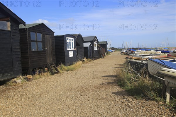 Dinghy boats and black wooden fishing sheds, River Ore, Orford, Suffolk, England, UK