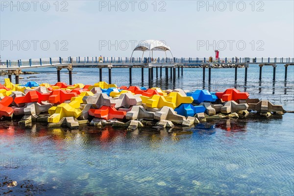 Large blocks of concrete in primary colors in water with boardwalk in background in Goseong, South