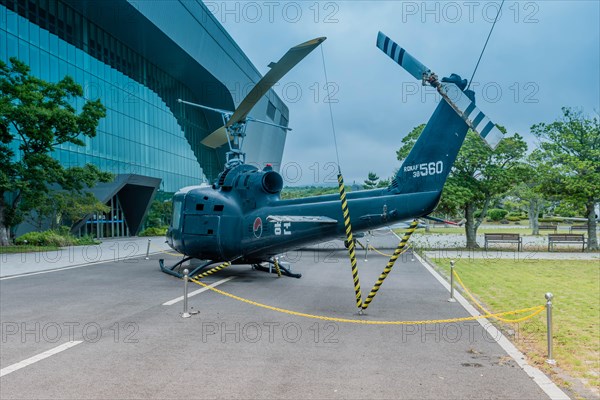 Bell UH-1B helicopter on pavement at museum under cloudy sky in Jeju, South Korea, Asia
