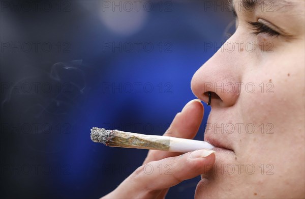 A woman smokes a joint during a demonstration in favour of legal marijuana use. The demonstrators