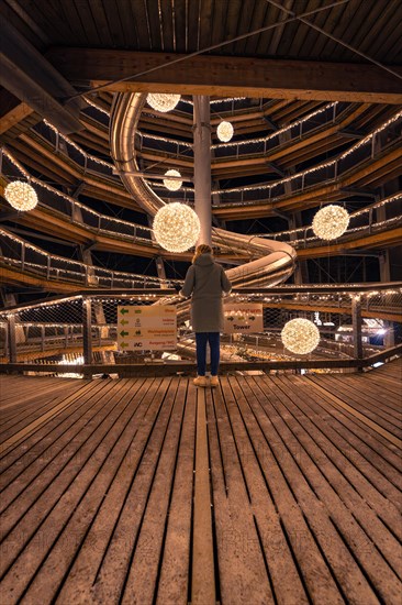 A person looks out onto a spiral-shaped, illuminated viewing platform, Enchanting forest dwellers,