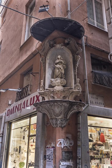 Sculpture of the Virgin Mary with canopy on a corner house in the historic centre, Genoa, Italy,