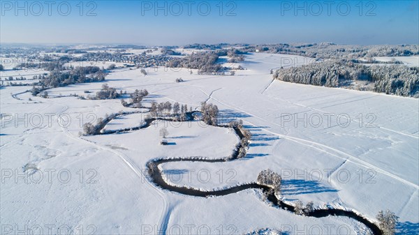 Drone shot of the river Schmutter meandering naturally through the snowy winter landscape of the