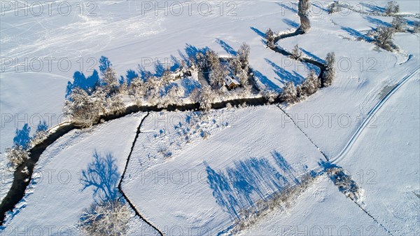 Drone shot of the river Schmutter meandering naturally through the snowy winter landscape of the