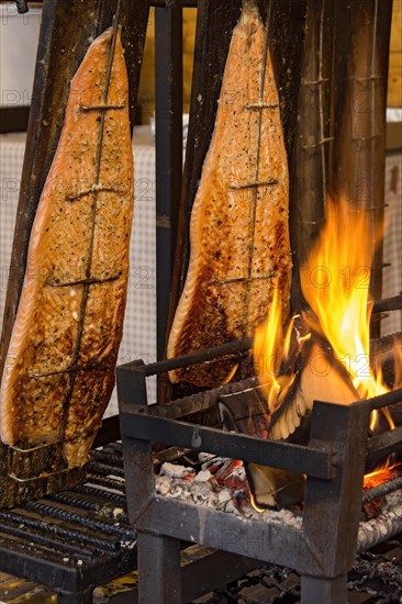 Flame-grilled salmon in a fire bowl, fillets of salmon grilled over an open flame, fish cooked,