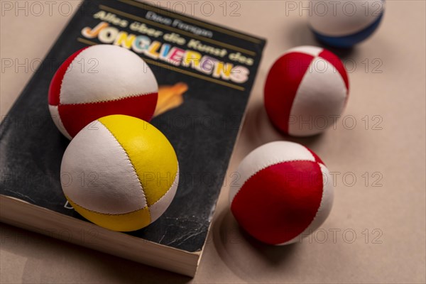 Juggling balls and a book about juggling on a white background, selective focus, studio shot,