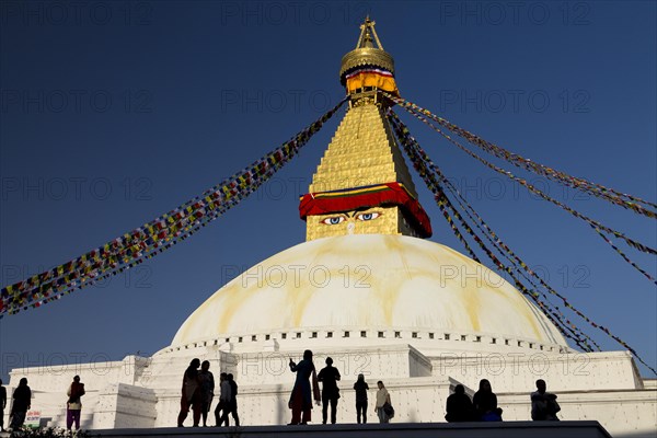 People gathered at Bouddhanath, the Bouddha Stupa, on a sunny, spring afternoon. It is the largest