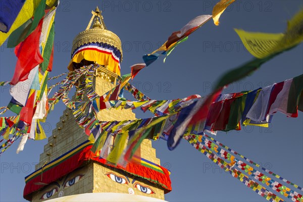 Golden spire of Boudhanath, the Bouddha Stupa, and colourful Buddhist prayer flags. It is the