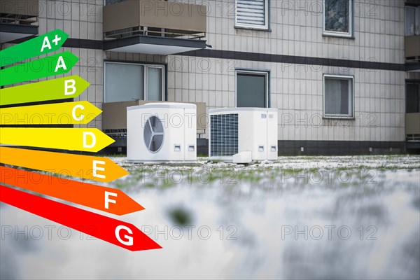 Two heat pumps in the snow in a meadow in front of an apartment block from the 1970s, graphic with