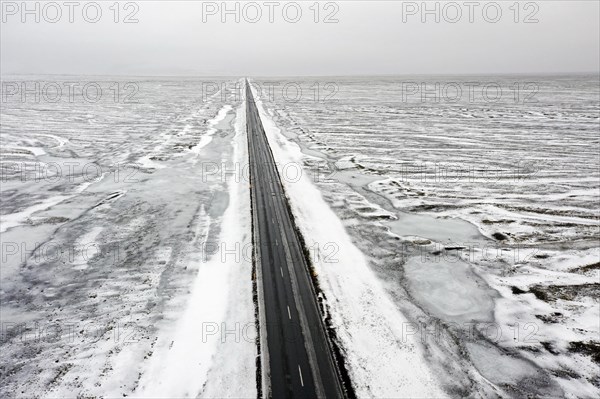 Aerial view over empty Route 1, Ring Road, two-lane national road in desolate snow covered winter