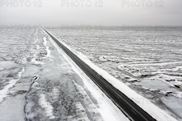 Aerial view over empty Route 1, Ring Road, two-lane national road in desolate snow covered winter