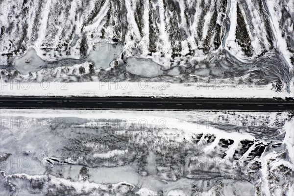 Aerial view over empty Route 1, Ring Road, two-lane national road in desolate snow covered winter