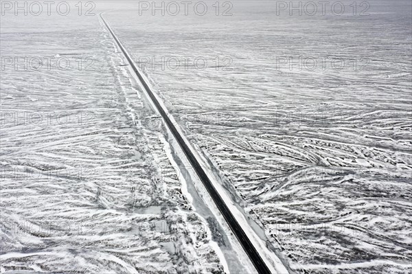 Aerial view over Route 1, Ring Road, two-lane national road in desolate snow covered winter