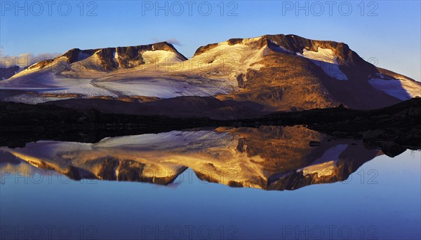 Early-morning light on the Fannaraken peaks with a mirror-like reflection in a glacial lake,