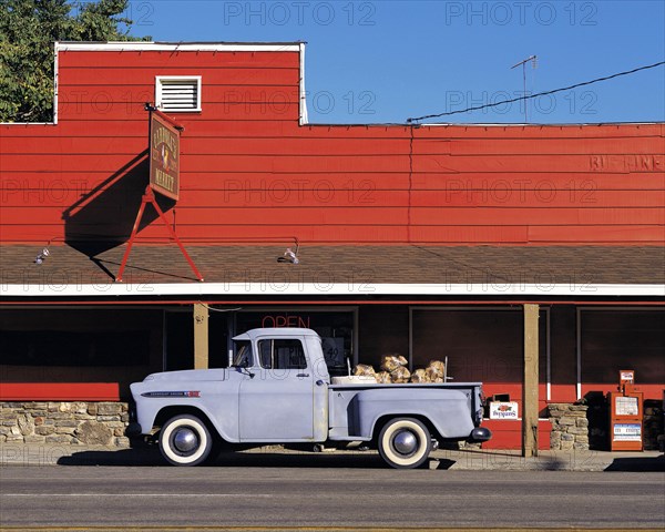 Old-style grey pick-up truck parked in front of red-painted store, California, USA, North America