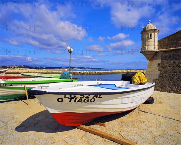 Boats on the beach at Lagos, with the old harbour defenses, the 17th century Forte Bandeira, under