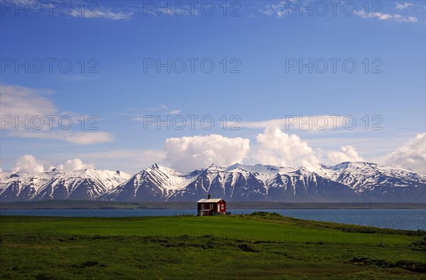 Wooden cabin on the shores of Eyjafjordur with the Kaldbakur mountains behind, near Dalvik,