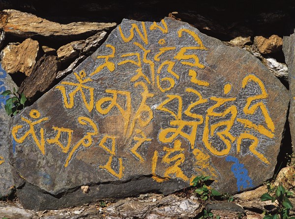 Carved mane-stone carrying the Buddhist message Om mane Padme hom by the side of a trail in east