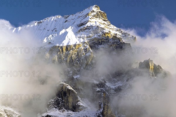 Afternoon mist and clouds gather around the dramatic crags and summit of an un-named peak in the