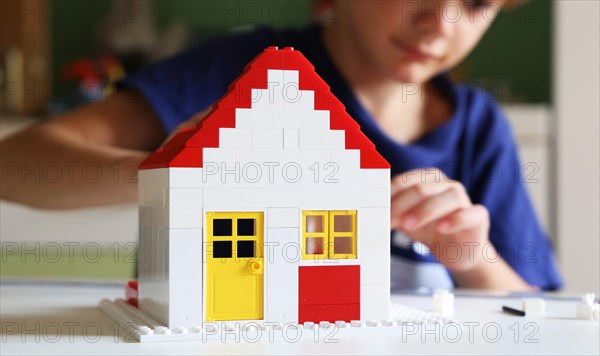 Symbolic image: Boy builds a house with building blocks