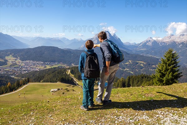 Hiking with children in Seefeld, Tyrol: Father shows his son the landscape. The snow-covered peak