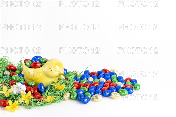 Chocolate eggs and a decorative chick surrounded by artificial grass as a festive decoration, white