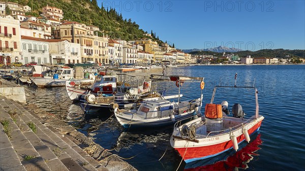 Small fishing boats at a sun-drenched Mediterranean harbour with mountains, Taygetos Mountains,