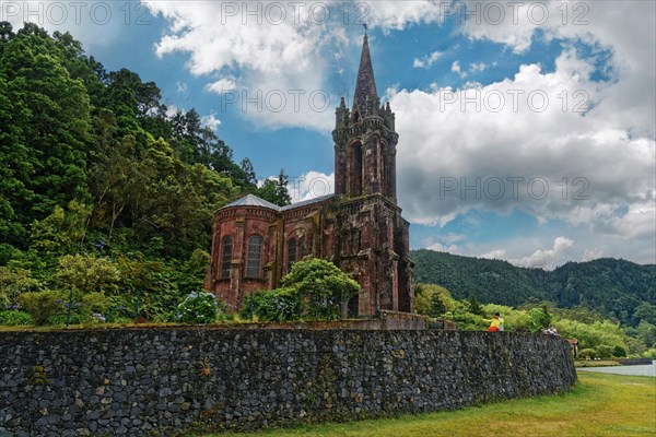 Old gothic church Capela de Nossa Senhora das Vitorias surrounded by trees and a stone wall against