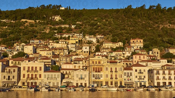 The morning light illuminates the lively coastal panorama and the busy harbour, Gythio, Mani,