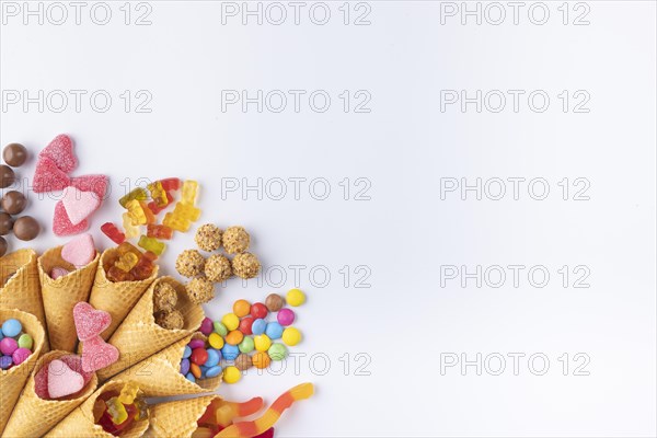 Colourful sweets, gummy bears, chocolate lentils falling out of ice cream cones, copy room, white