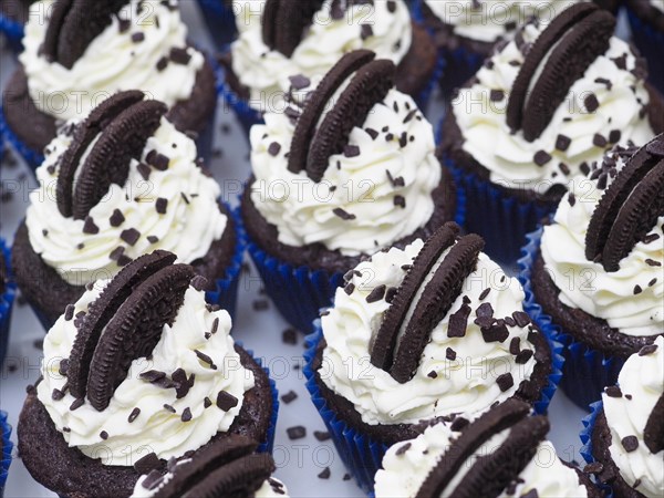 Production of A group of unhealthy dark chocolate cupcakes with sweet frosting cream and cookie