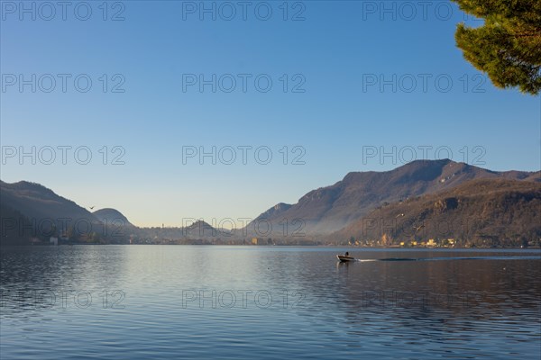 Boat Travel on Lake Lugano with Mountain and City in a Sunny Day with Clear Sky in Porto Ceresio,