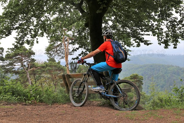 Mountain biker taking a break on a bench in the Palatinate Forest near the Weinbiet above Neustadt