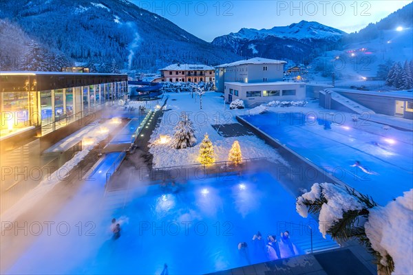 Snow-covered rock spa in winter, thermal bath with Christmas lights at dusk, Bad Gastein, Gastein