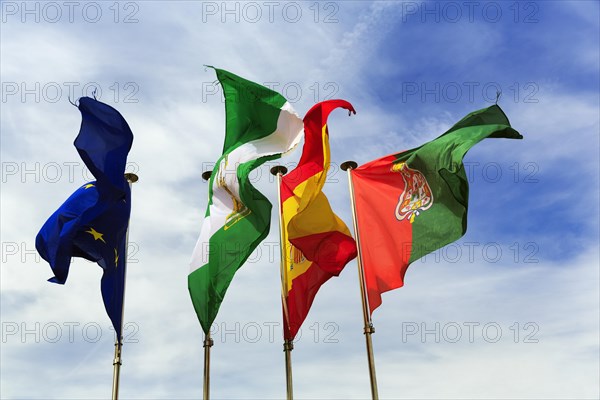 Four flags next to each other, fluttering in the wind, strong wind, European Union, Andalusia,
