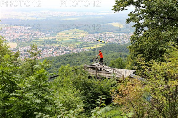 Mountain biker stands on the launch ramp for hang-gliders below the Melibokus and looks out over
